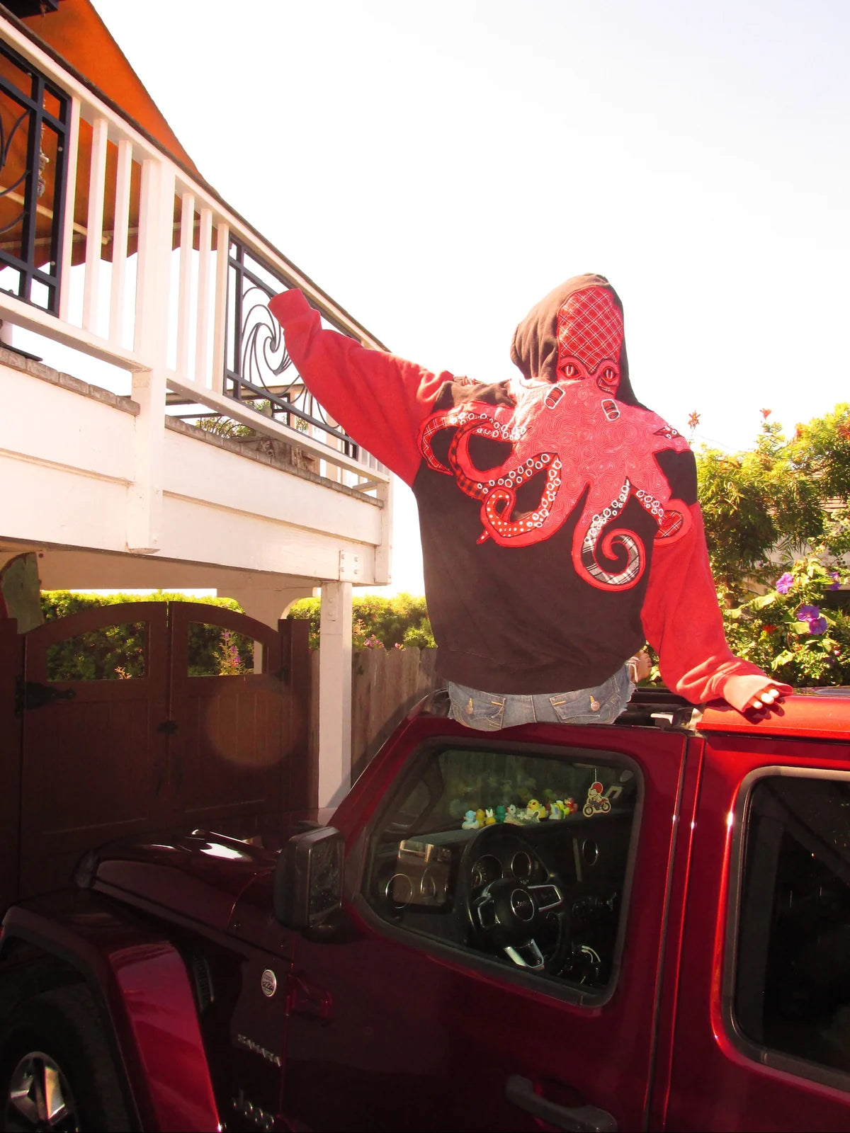 The octopus hoodie seen from behind on a red Jeep, with artwork extending onto the hood and sleeves.